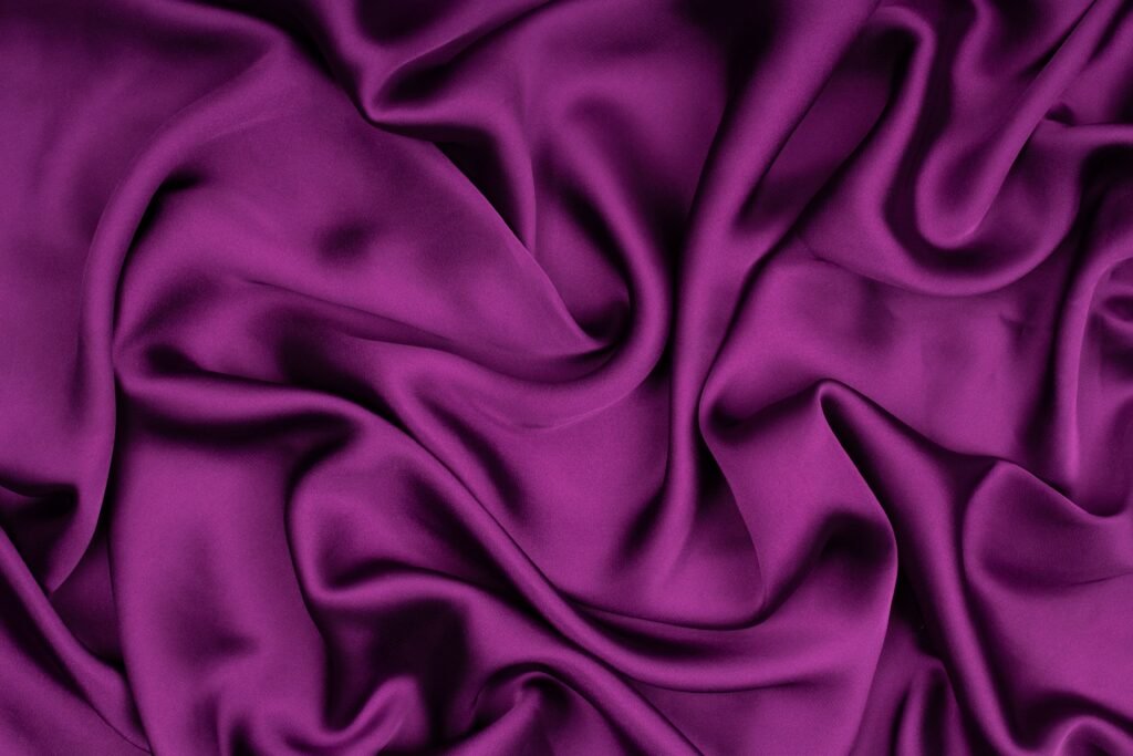 Close-up of luxurious purple silk fabric with elegant folds and softness.